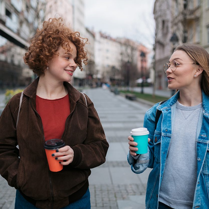 Two Friends Walking With a Coffee