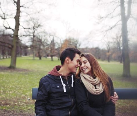 A couple hugging on a bench in the park
