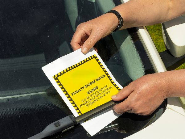 Parking enforcement notice being put onto windscreen of car