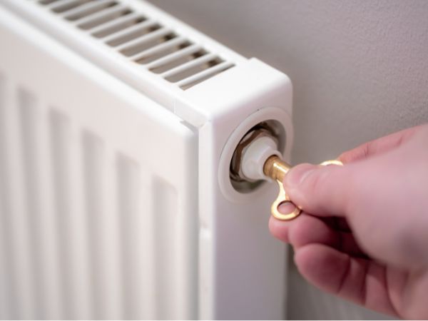 Hand with radiator key bleeding the radiator